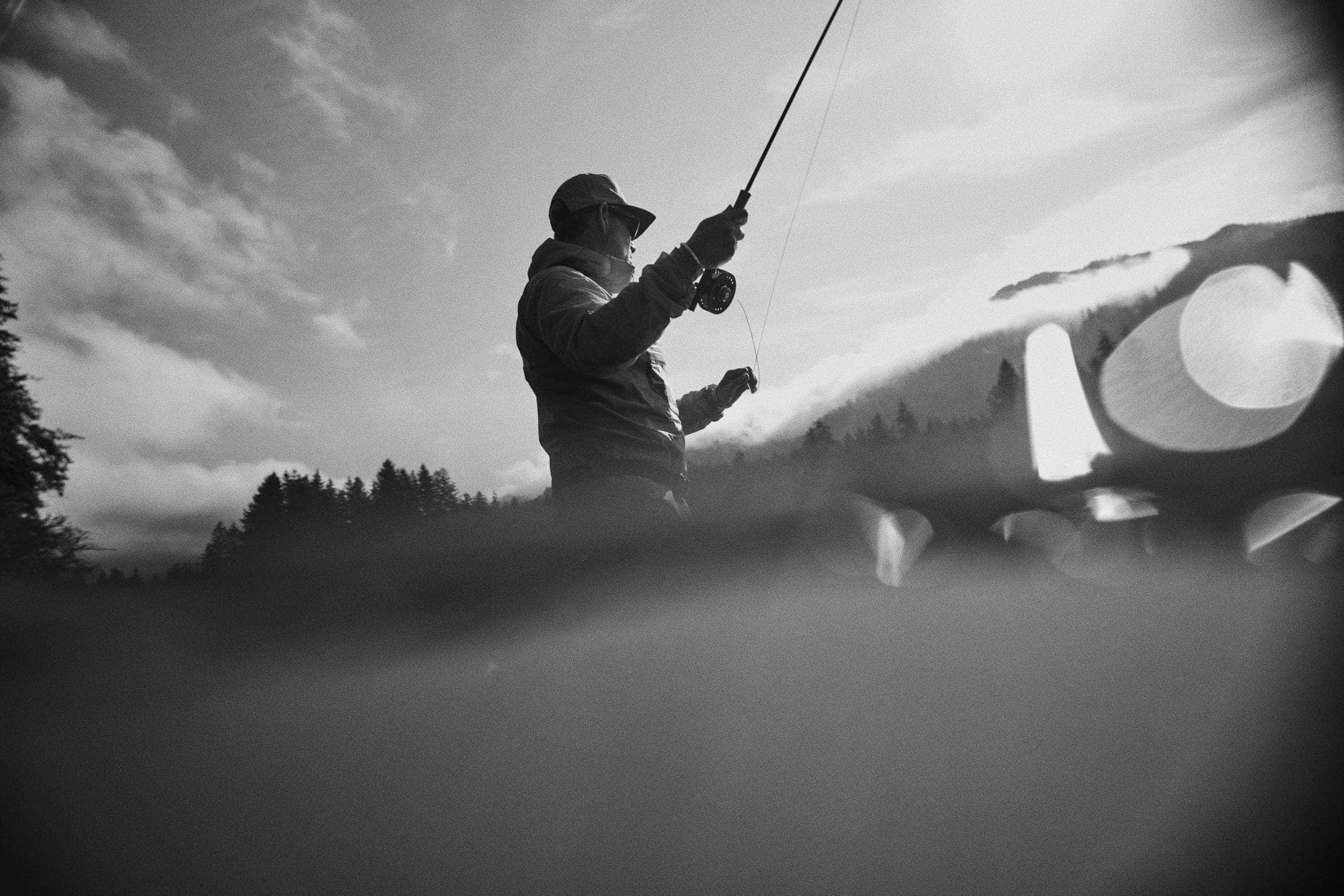 Angler casting in misty water